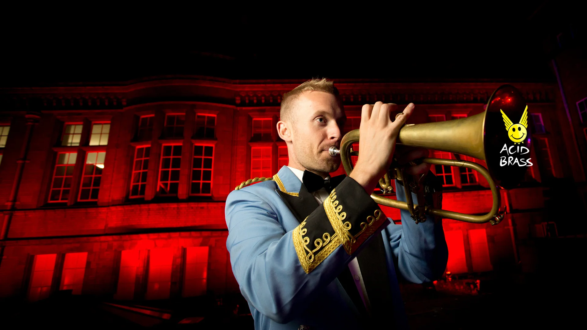 An Acid Brass musician performing beneath red stage lighting